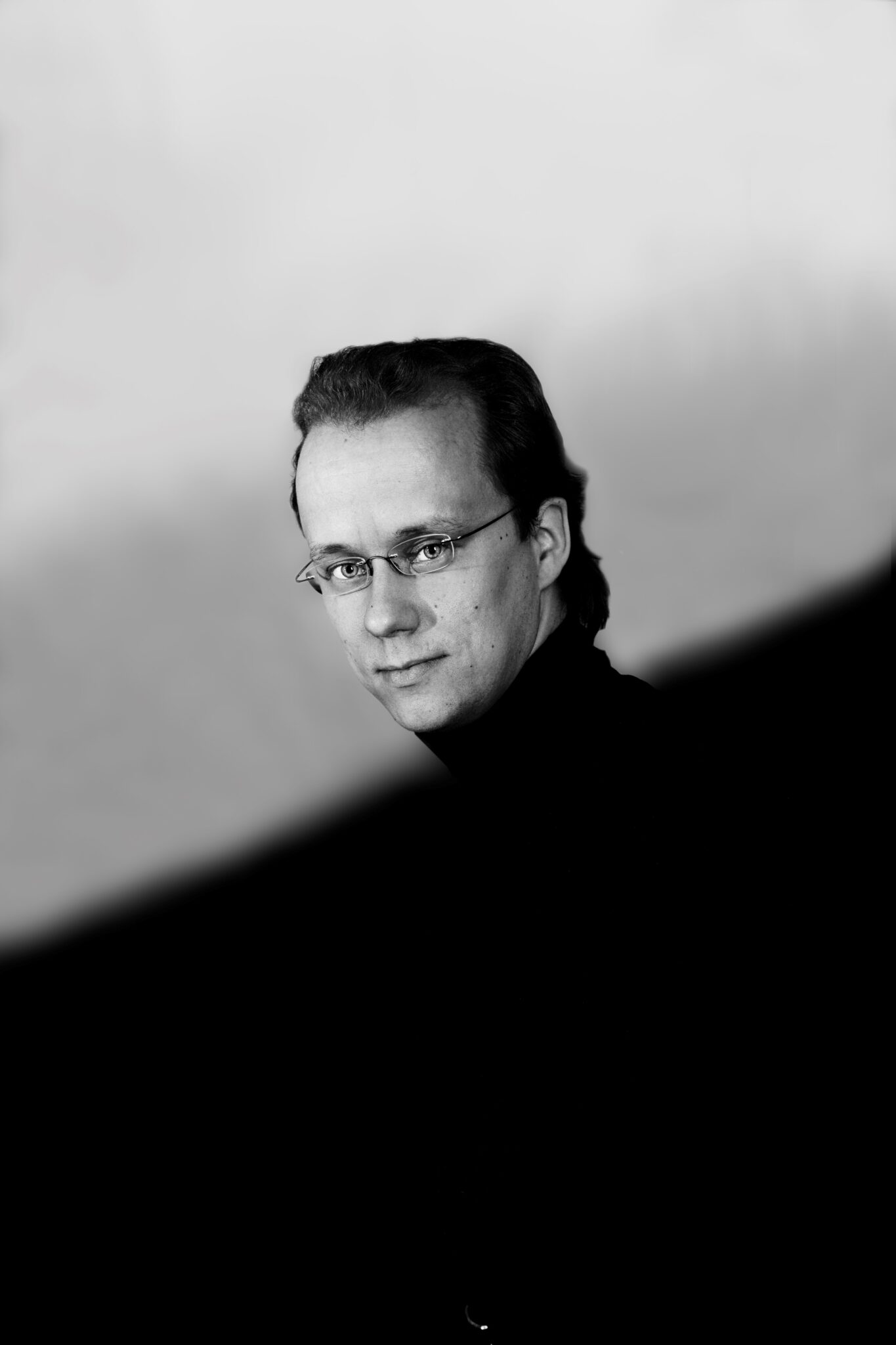 Mustavalkoisessa taidekuvassa Hannu Ala, silmälasipäinen tummatukkainen pianisti katsoo kohti kameraa.